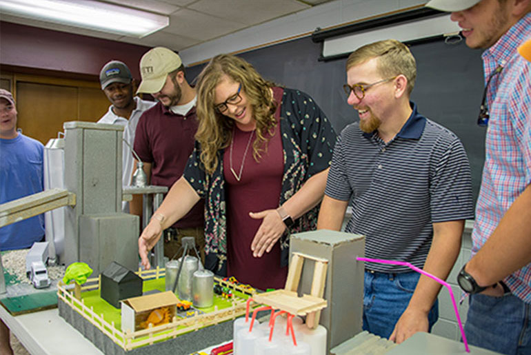 female professor looks at models developed by students